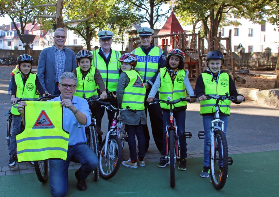 Bildunterzeile: Warnwesten machen den Schulweg sicherer: v.l. Franz-Josef Fichna, Fahrradbeauftragter Kreis Paderborn, Polizeioberkommissar Horst-Edgar Schäfers, Polizeihauptkommissarin Ingrid Sandbote und vorne hockend: Jens Nacke, Schulleiter Gesamtgrundschule Karl mit Schülerinnen und Schülern, © Amt für Presse- und Öffentlichkeitsarbeit, Kreis Paderborn, Maike Delang Warnwesten für Kinder